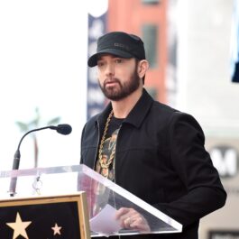Artistul Eminem cu o șapcă pe cap în fața unui pupitru
