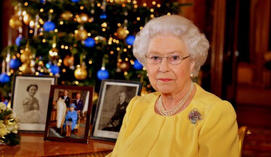 Regina Elisabeta într-o bluză galbenă în fața biroului la Castelu Windsor de Crăciun în anul 2013