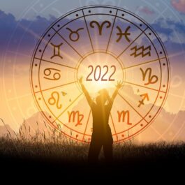 O femeie care stă în fața unui apus pe care se află harta cu horoscopul anului 2022