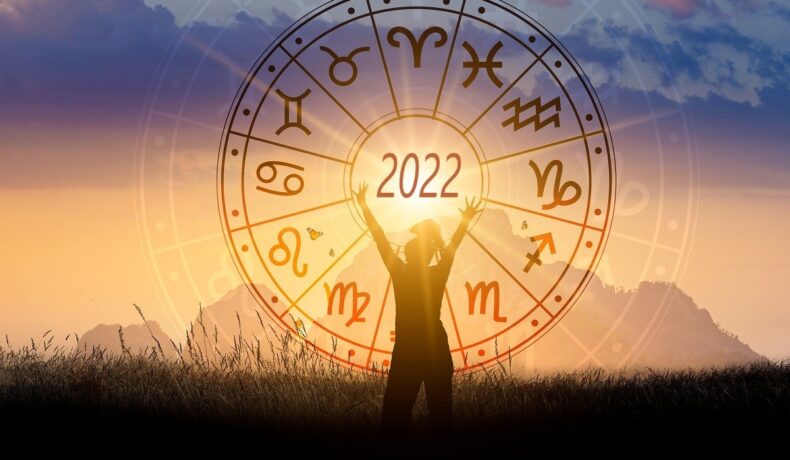 O femeie care stă în fața unui apus pe care se află harta cu horoscopul anului 2022