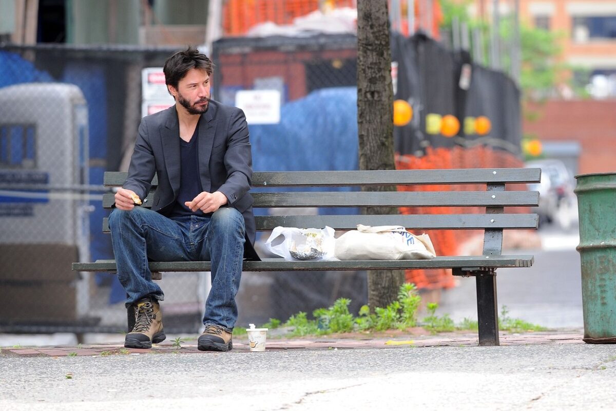 Keanu Reeves în timp ce stă pe o bancă singur și mănâncă în anul 2010