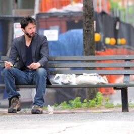 Keanu Reeves în timp ce stă pe o bancă singur și mănâncă în anul 2010
