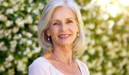 O femeie în vârstă cu părul alb care zâmbește pentru a indica unul din principalele obiceiuri la care e indicat să renunți după vârsta de 60 de ani