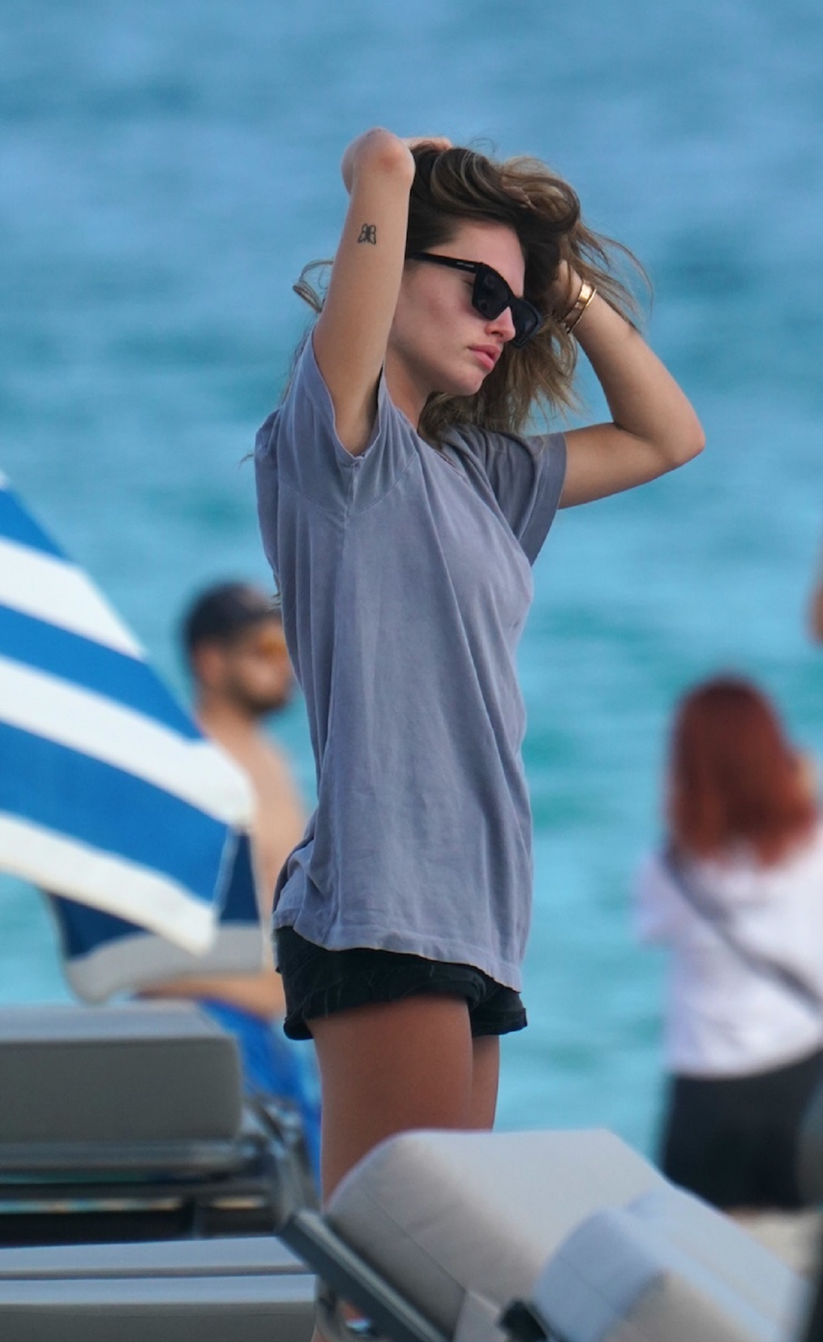 Thylane Blondeau în timp ce își aranjează părul și poartă un tricou albastru și o pereche de pantaloni scurți negri la plajă în Miami