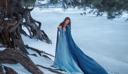 O femeie frumoasă care poartă o rochie albastră într-o pădure plină cu zăpadă pentru a reprezenta una din cele trei zodii ghinioniste în ziua de 23 decembrie 2021