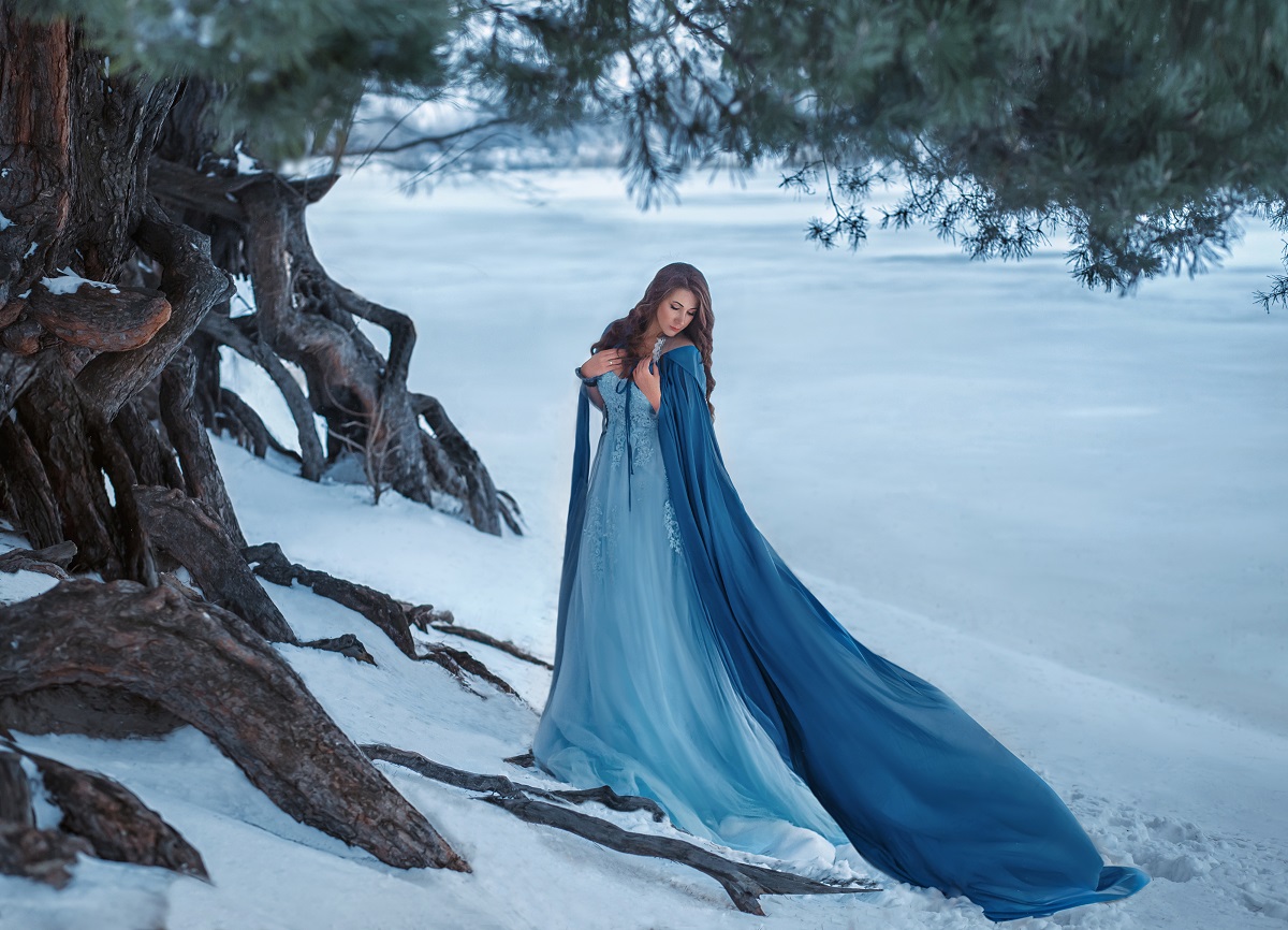 O femeie frumoasă care poartă o rochie albastră într-o pădure plină cu zăpadă pentru a reprezenta una din cele trei zodii ghinioniste în ziua de 23 decembrie 2021
