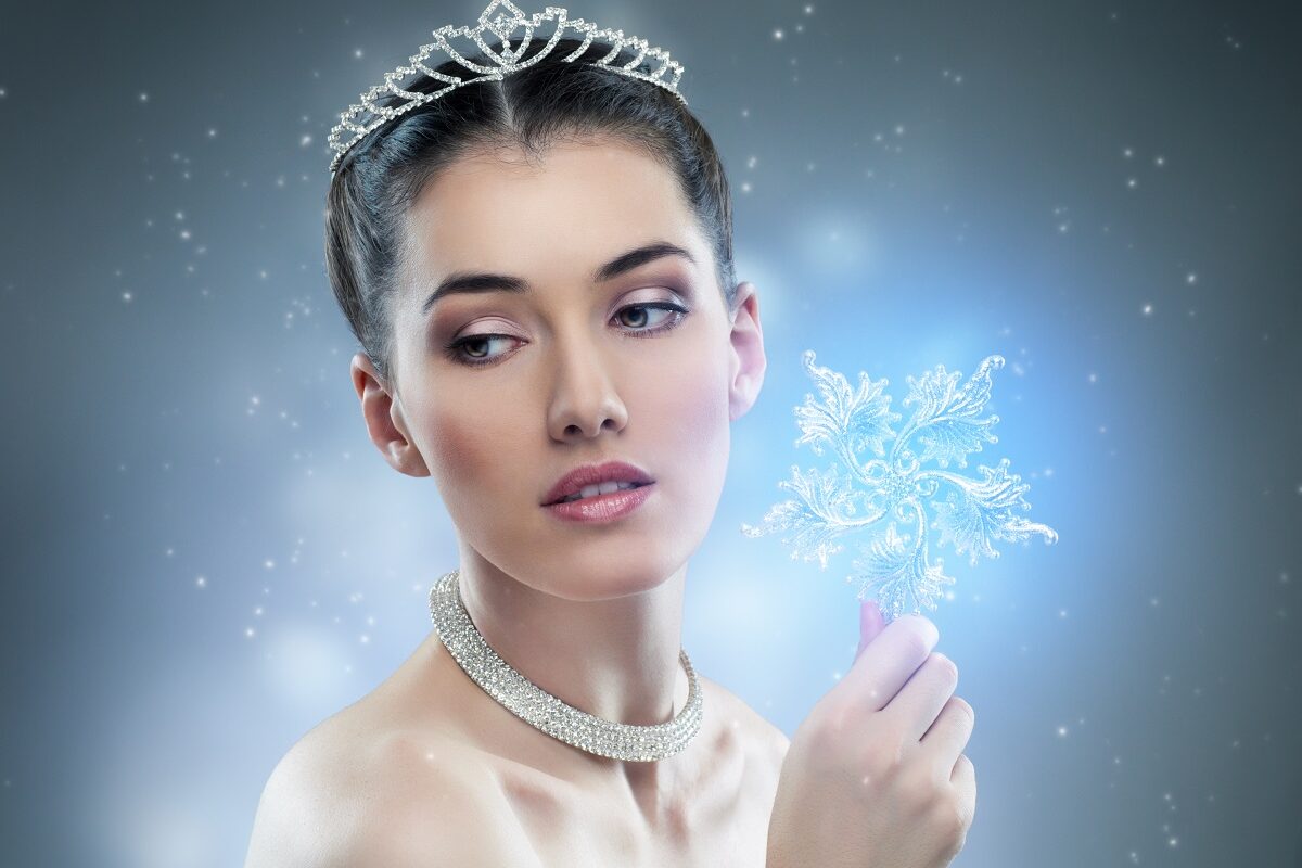 O femeie frumoasă cu părul prin care ține în mână un fulg mare de nea și poartă o coroniță albă pentru a reprezent una din cele trei zodii norocoase în ziua de 31 decembrie 2021