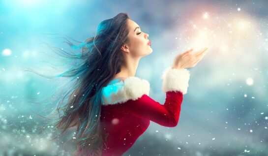 O femeie frumoasă într-un costum de Crăciuniță care suflă sclipici pentru a reprezenta una din cele trei zodii norocoase în ziua de 9 decembrie 2021