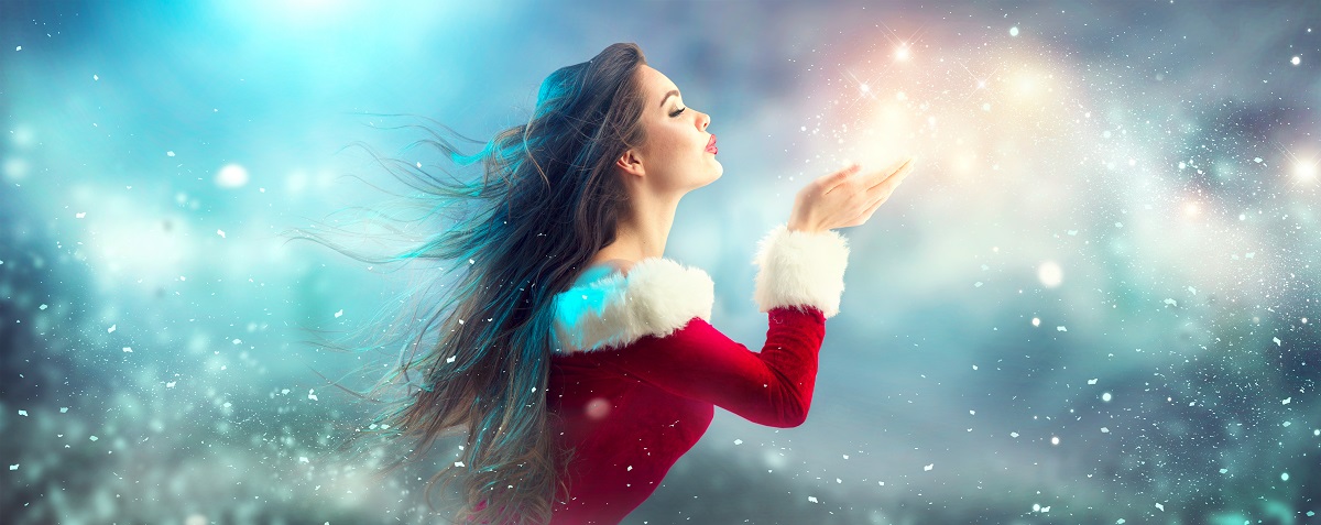 O femeie frumoasă într-un costum de Crăciuniță care suflă sclipici pentru a reprezenta una din cele trei zodii norocoase în ziua de 9 decembrie 2021