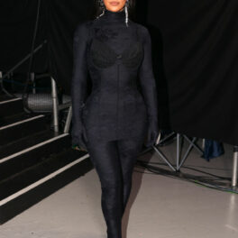 Kim Kardashian, într-o salopetă mulată neagră, cu o rochie și sutien peste și ochelari de soare la ochi