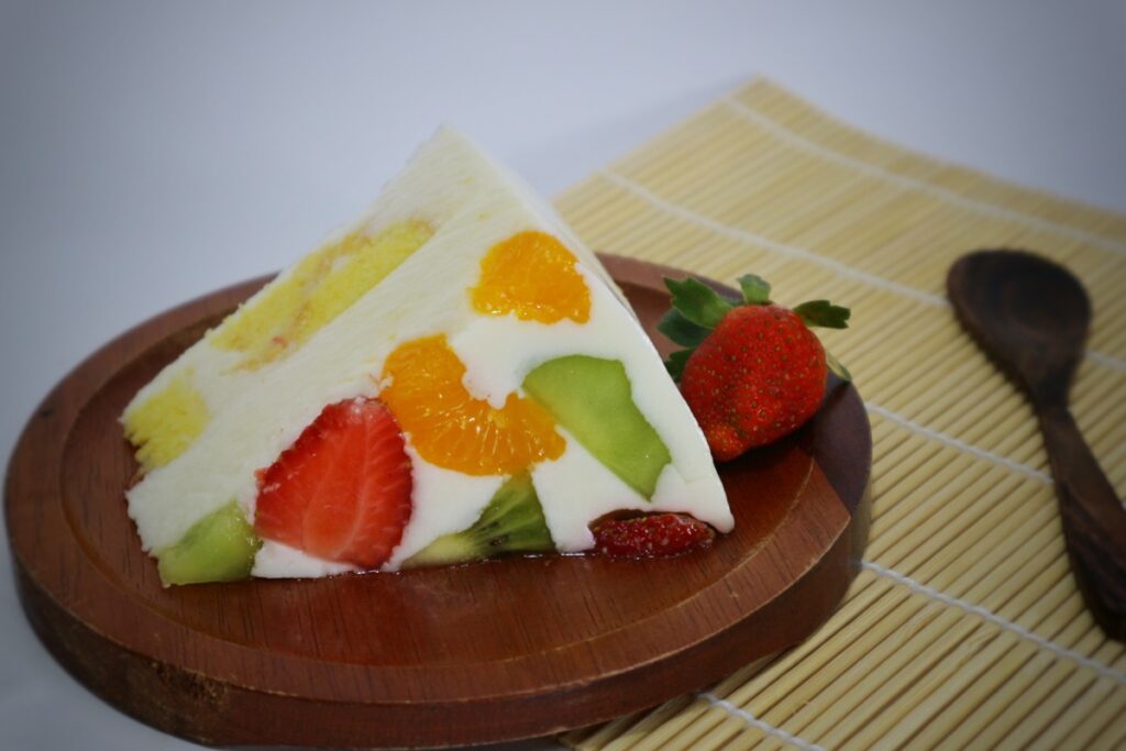 Piece of diploma cake with fruits and cream on a brown plate