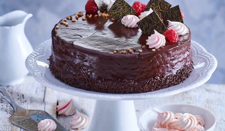 Tort Sacher decorat cu bucăți de ciocolată, bezele, zmeură și nuci