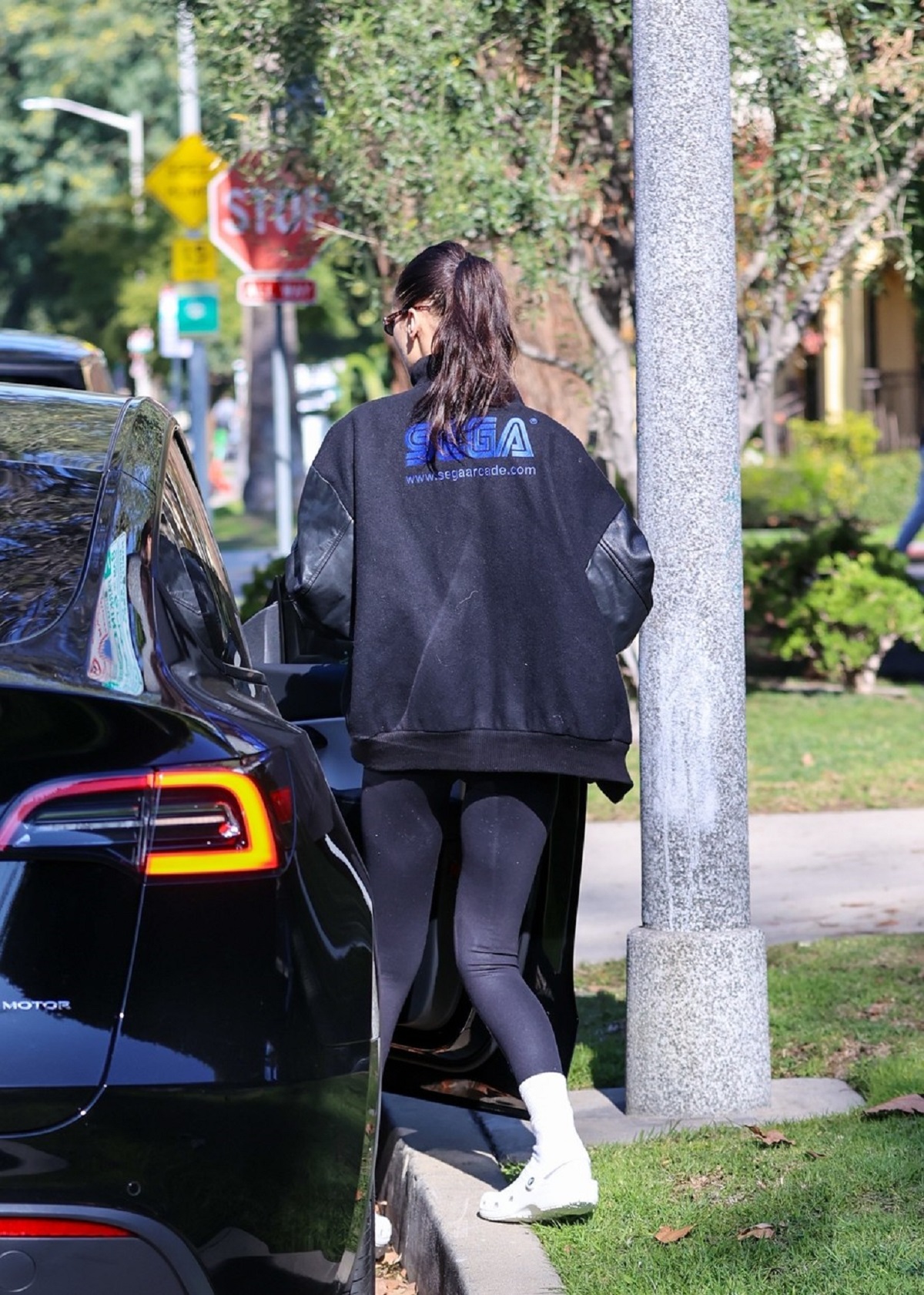 Bella Hadid cu spatele într-o pereche de colanți negri și o haină neagră