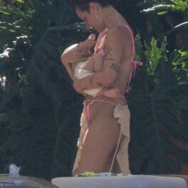 Halsey într-un costum de baie roz în timp ce își ține în brațe bebelușul
