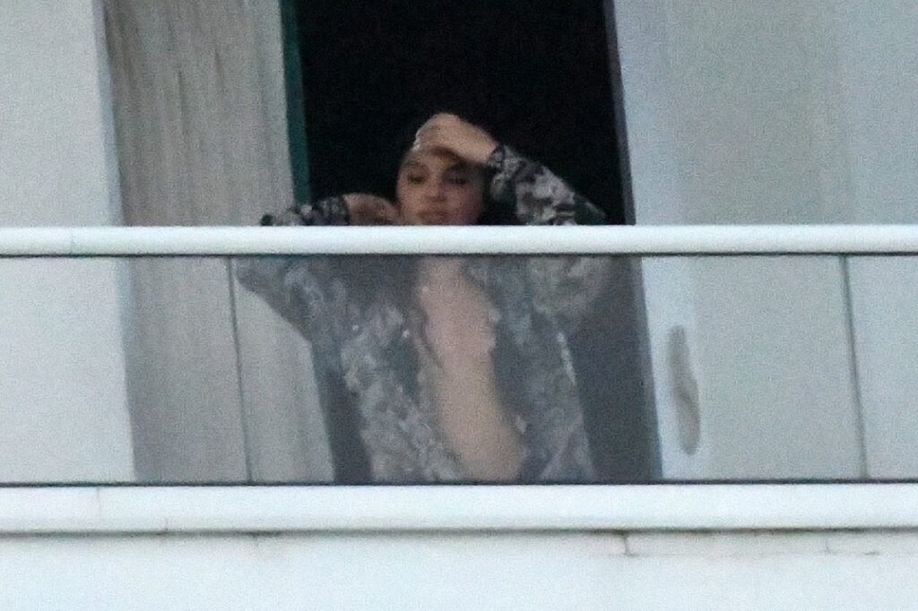 Julia Fox într-o cămașă în timp ce iese la balconul unui iaht de lux