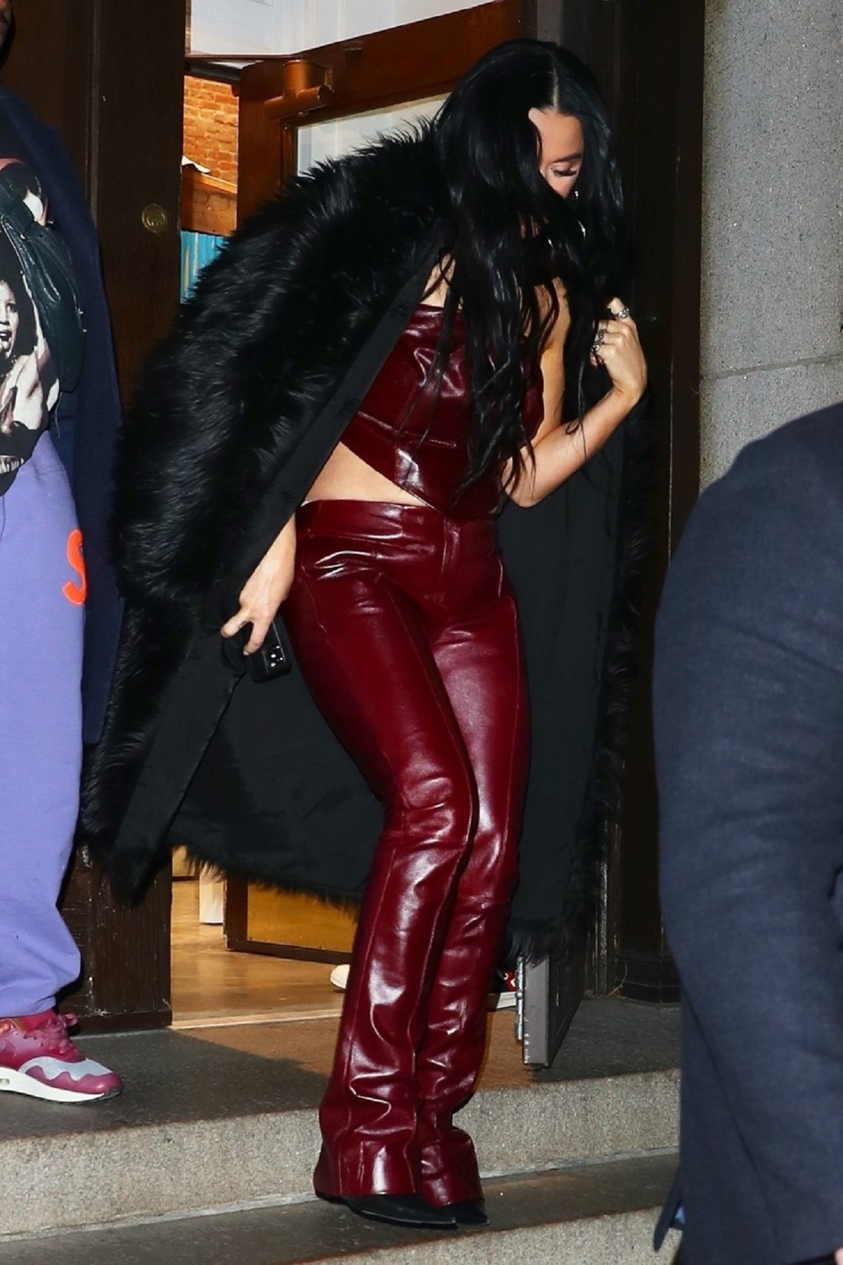 Katy Perry, purtând un costum din piele burgundy în timp ce coboară scările dintr-o clădire din New York