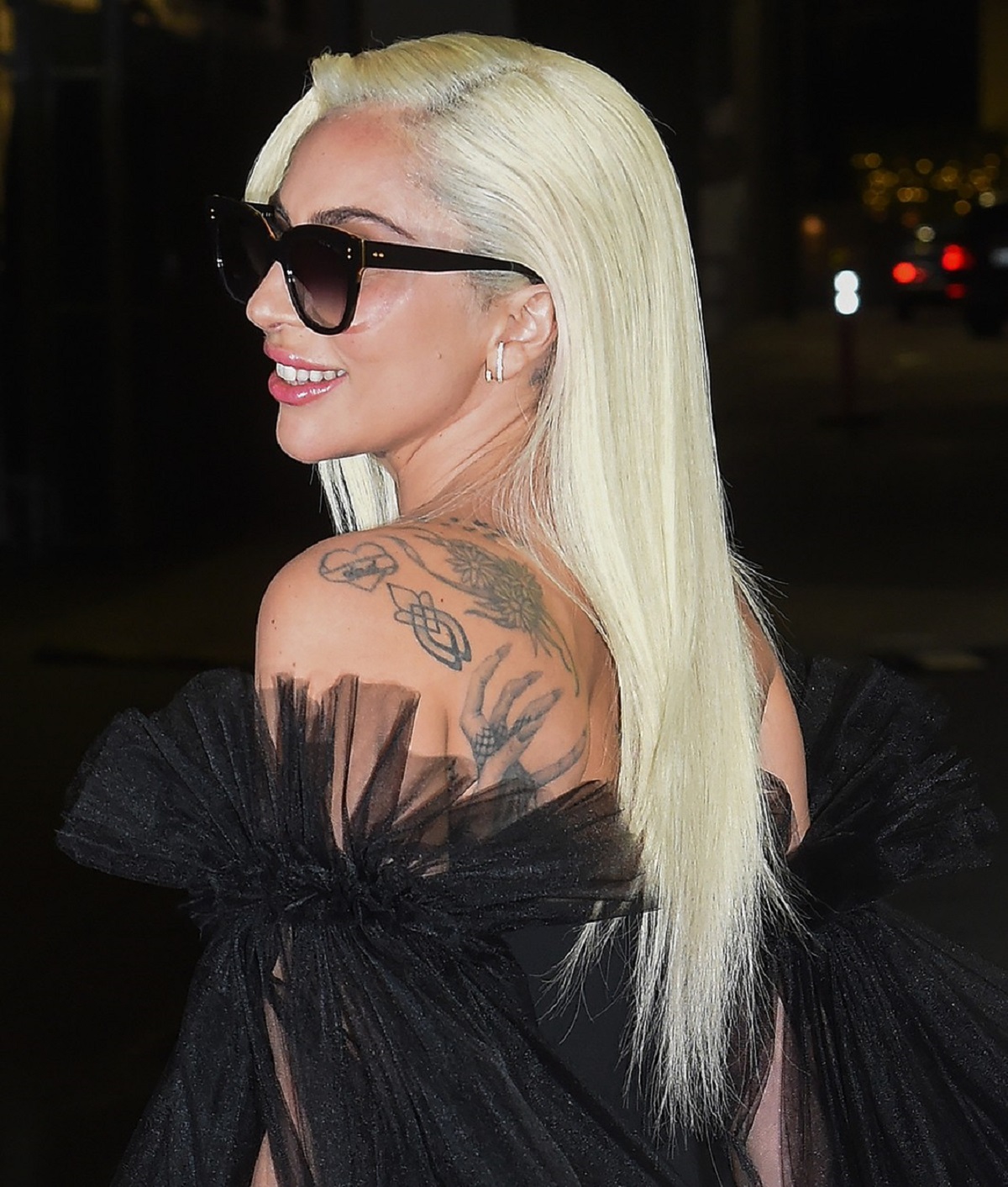 Lady Gaga într-o rochie mulată neagră în timp ce își lasă la vedere tatuajele de pe umăr