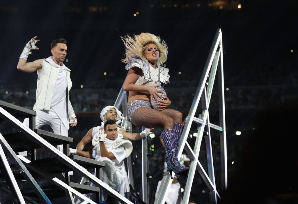 Lady Gaga pe scenă la Super Bowl LI în timp ce prinde o minge de fotbal american