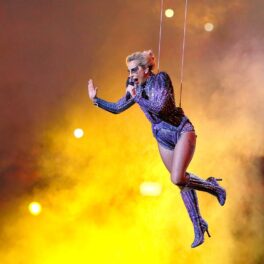 Lady Gaga în timp ce poartă un costum de scenă violet și atârnă pe scenă cu ajutorul unor cabluri din timpul spectacolului ținut la Super Bowul LI 2017