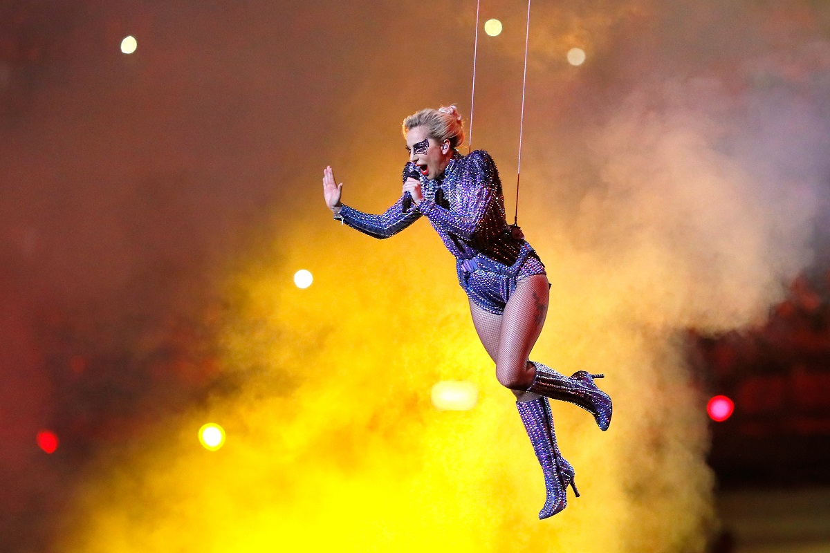 Lady Gaga în timp ce poartă un costum de scenă violet și atârnă pe scenă cu ajutorul unor cabluri din timpul spectacolului ținut la Super Bowul LI 2017