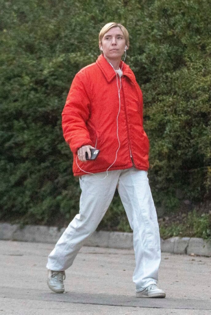 Lykke Li, noua iubită a lui Brad Pitt, într-o pereche de pantaloni de trening și o geacă roșie în timp ce se plimbă prin partier și ascultă muzică