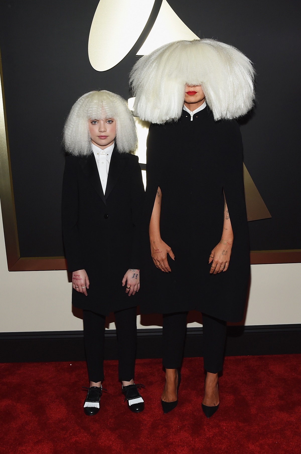 Maddie Ziegler într-un costum negru alături de artista Sia la Premiile Grammy