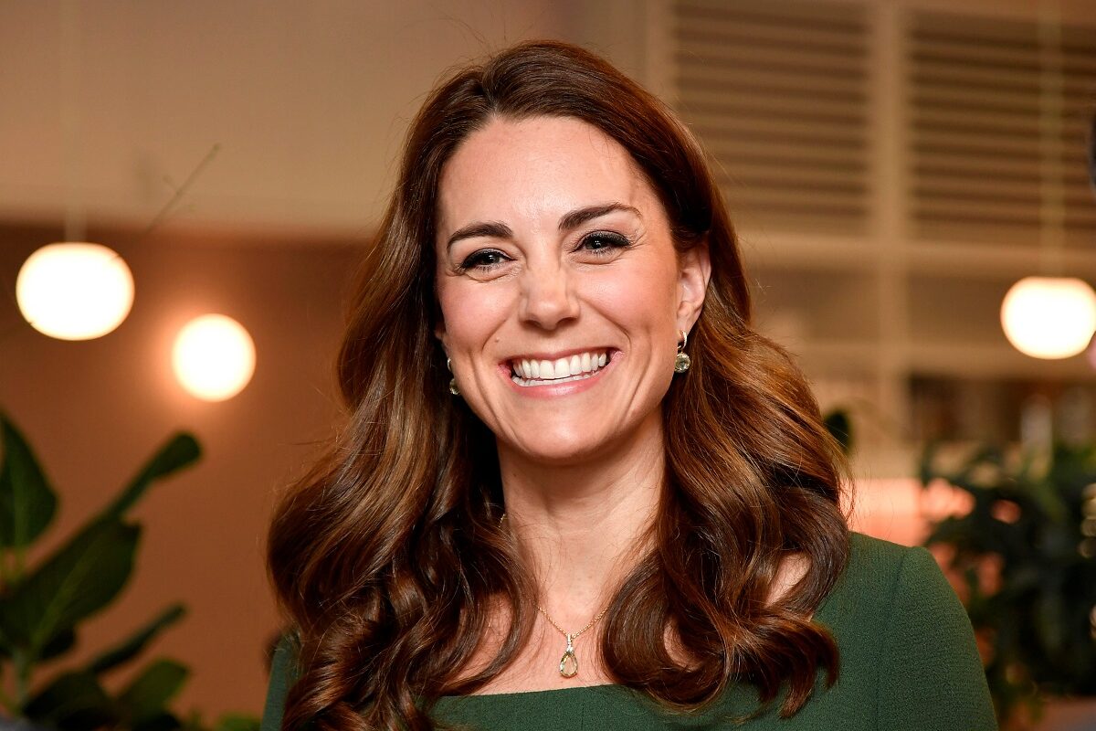 Kate Middleton într-o bluză verde în timp ce zâmbește