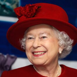 Regina Elisabeta într-un costum roșu cu o pălărie
