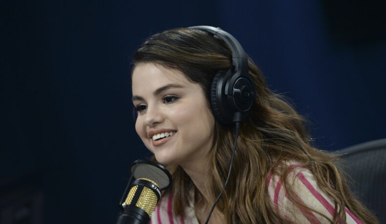 Selena Gomez cu o pereche de căști pe cap în fața unui microfon la un interviu din 2011