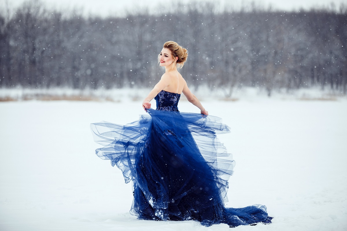 O femeie frumoasă care poartă o rochie albastră pe un câmp acoperit cu zăpadă pentru a reprezenta una din cele trei zodii norocoase în ziua de 6 ianuarie 2022