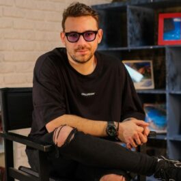Andrei Niculae, într-un decor cu multe fotografii, pe scaun, la interviul CaTine.ro