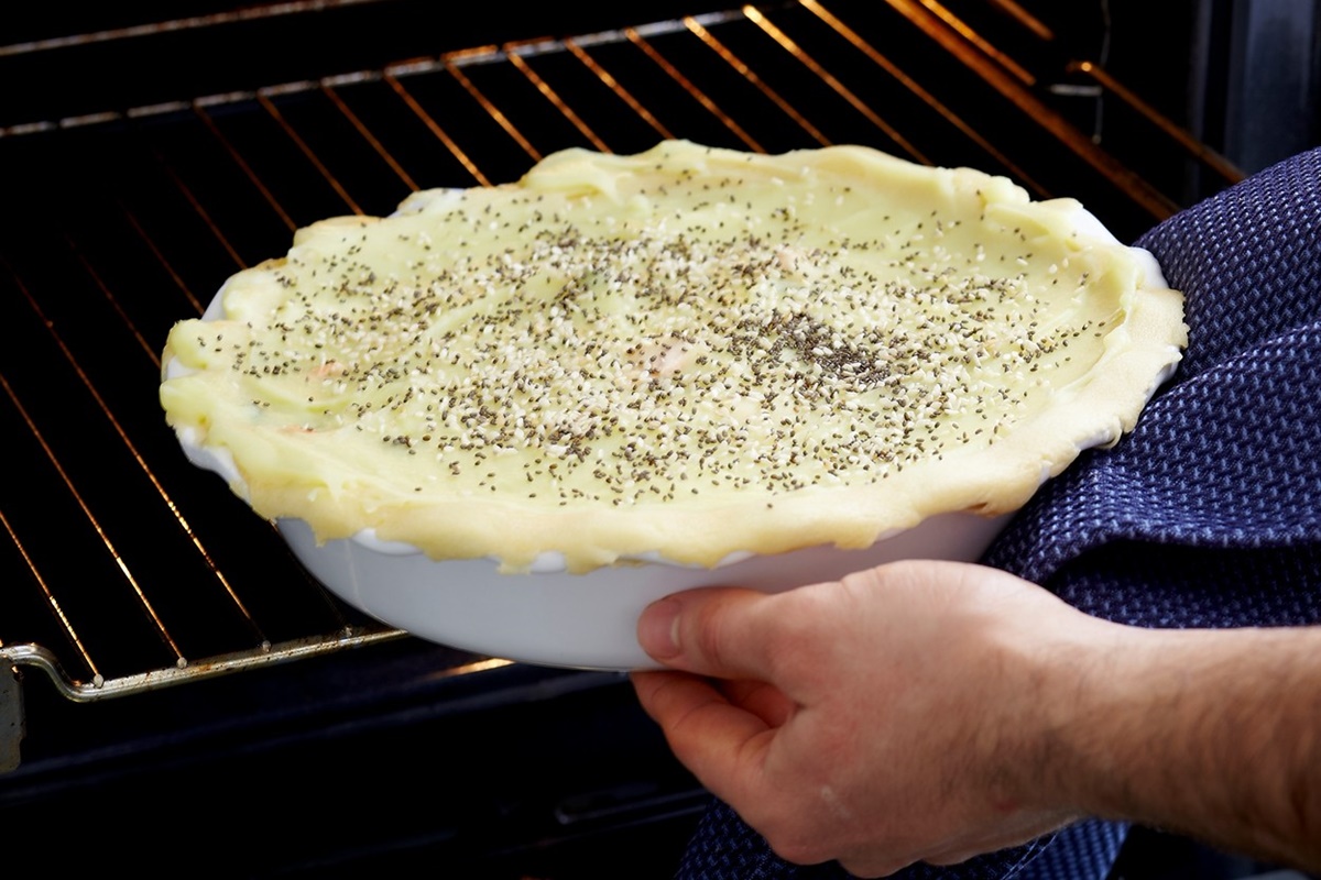 Pasul de introducere la cuptor a formei de copt cu quiche cu somon și praz, sub crustă din piure de cartofi