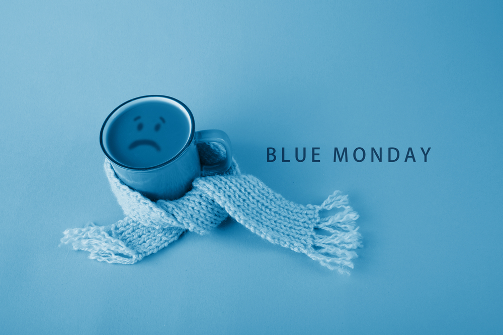 Imagine cu o cană acoperită de un fular, cu o față tristă, ce reprezintă Blue Monday 2022