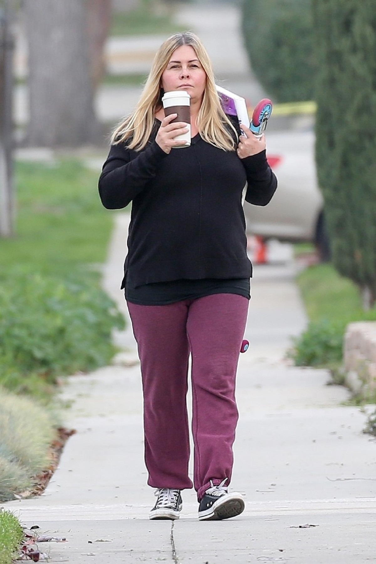 Nicole Eggert într-o bluză neagră și o pereche de pantaloni mov în timp ce se plimbă pe stradă