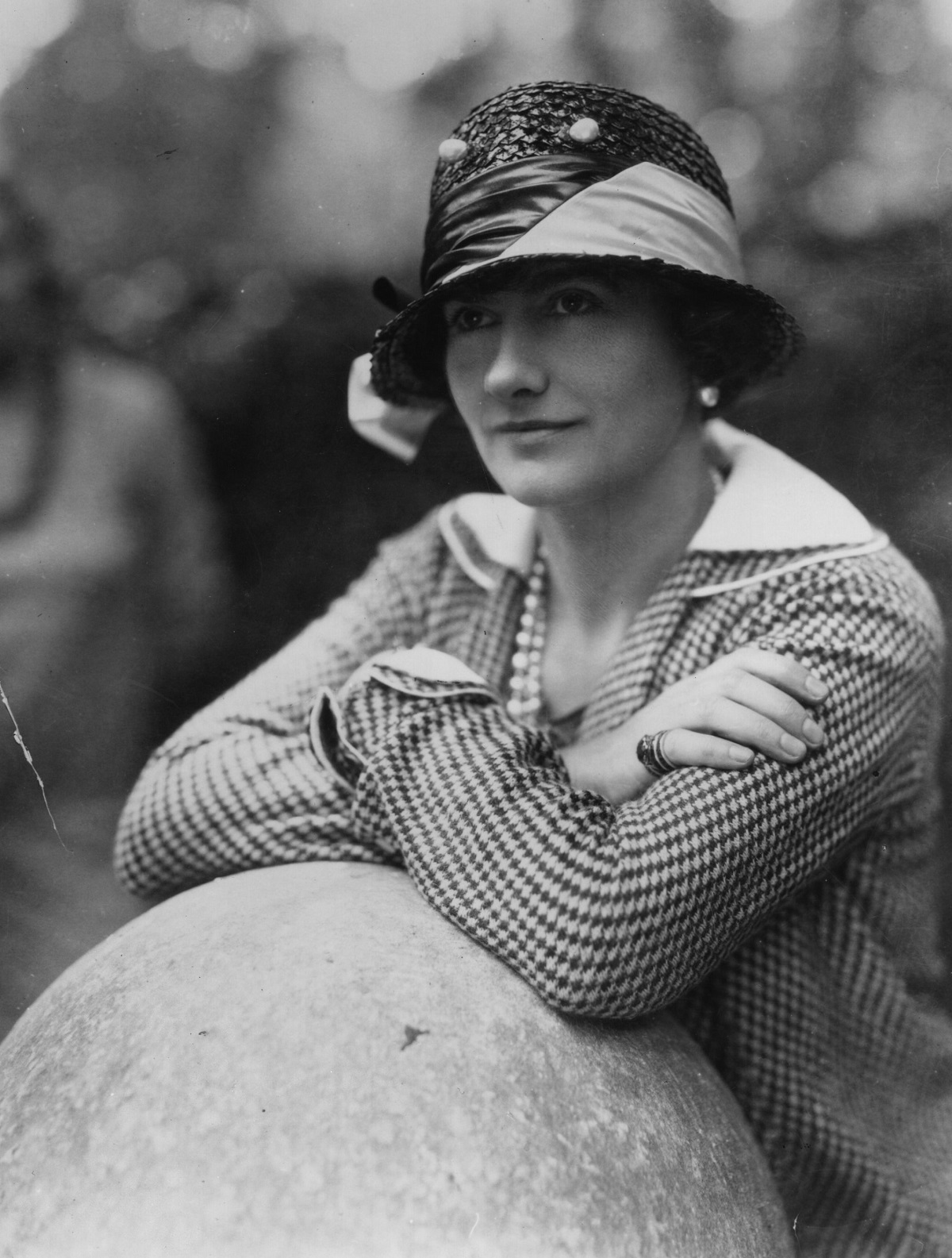 Coco Chanel în timp ce privește în zare cu o pălărie pe cap