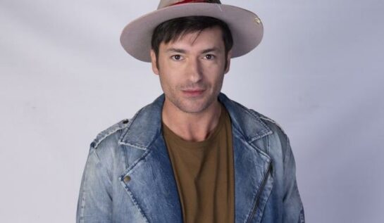 Radu Vâlcan, cu pălărie pe cap, poză la panou