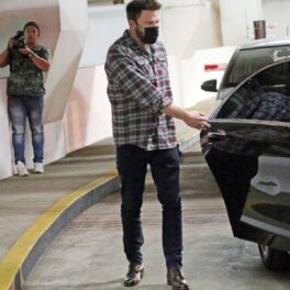 Ben Afflec într-o cămașă în carouri în timp ce deschide portiera mașinii în care se află Jennifer Lopez