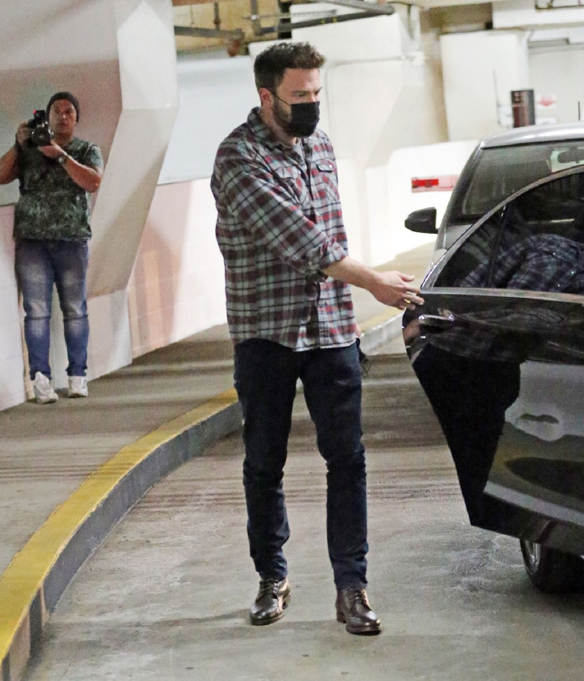 Ben Afflec într-o cămașă în carouri în timp ce deschide portiera mașinii în care se află Jennifer Lopez