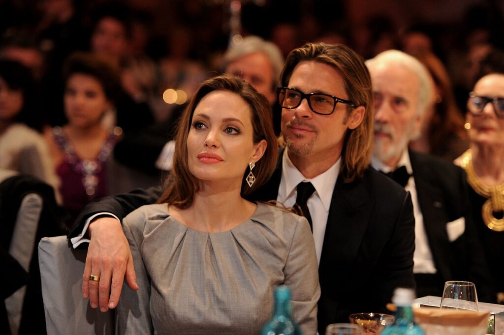 Angelina Jolie într-o rochie argintie în timp ce stă la o masă alături de Brad Pitt după ce au loat parte la Cinema fot peace Gala din anul 2012