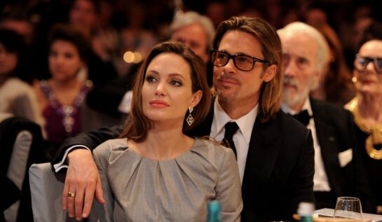 Angelina Jolie într-o rochie argintie în timp ce stă la o masă alături de Brad Pitt după ce au loat parte la Cinema fot peace Gala din anul 2012