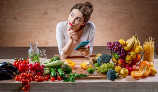 O femeie frumoasă care stă în fața unei mese cu alimente care au calorii negative