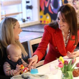 Kate Middleton îmbrăcată într-un sacou roșu în timp ce stă de vorbă cu o mămică și fiul acesteia în cadrul turului regal din Danemarca