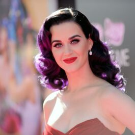 Katy Perry cu părul violet în timp ce pozează pe covorul roșu la un eveniment public