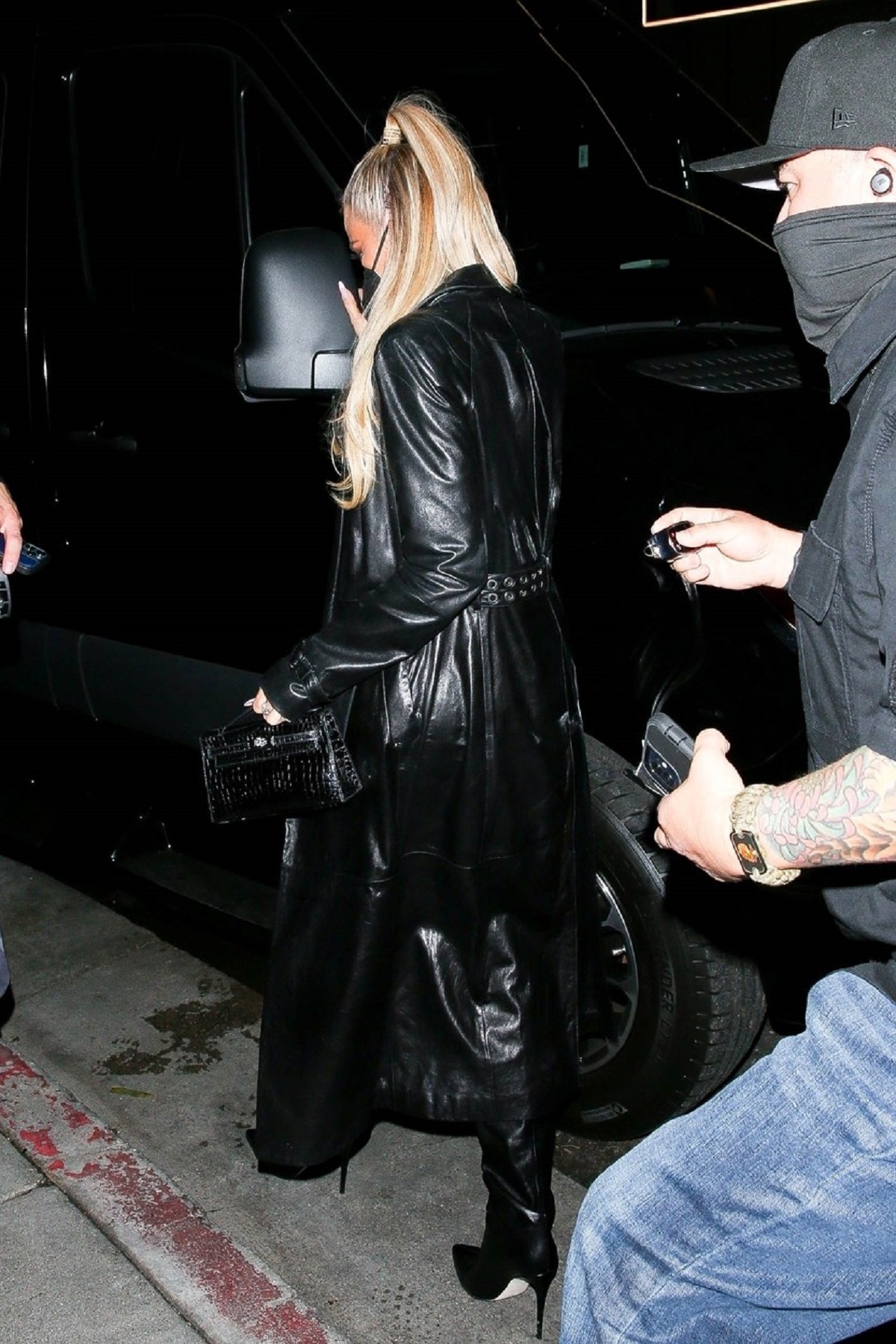 Khloe Kardashian într-un palton negru în timp ce părăsește petrecerea găzduită de Justin Bieber
