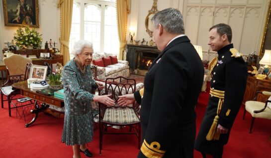 Regina Elisabeta îmbrăcată- întro rochie cu imprimeu floral în timp ce se prijină într-un baston și ia parte la o întâlnire oficială de la Castelull Windsor
