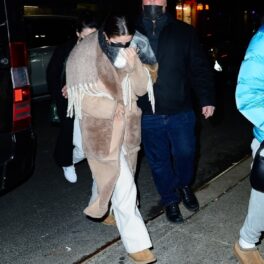 Selena Gomez purtând un palton oversize maro în timp ce încearcă să se ascundă de fotografii prezenți