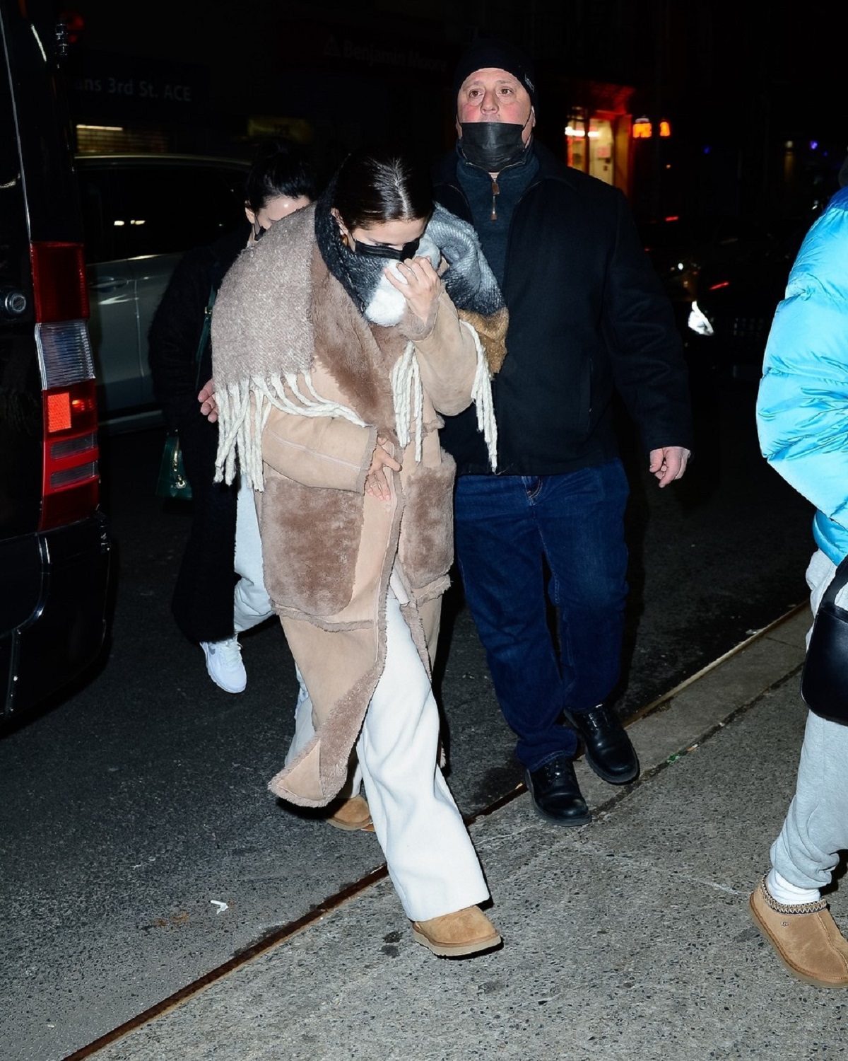 Selena Gomez purtând un palton oversize maro în timp ce încearcă să se ascundă de fotografii prezenți