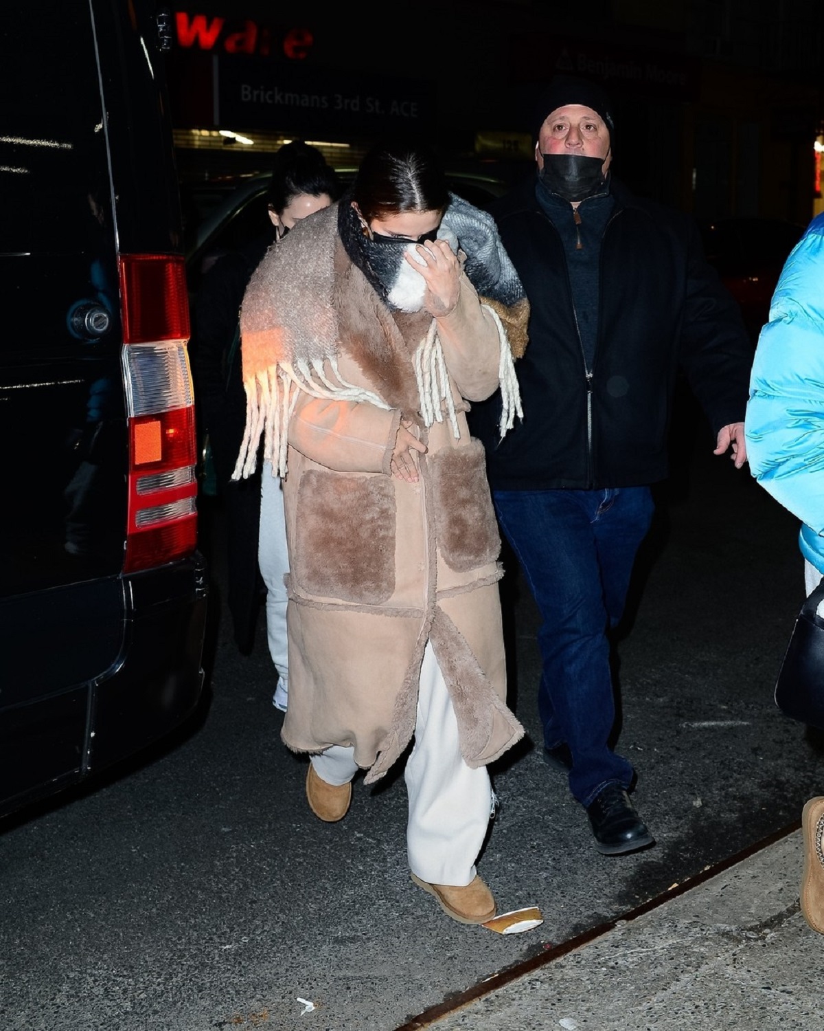 Selena Gomez îmbrăcată într-un palton maro în timp ce încearcă să se ascundă de fotografii prezenți