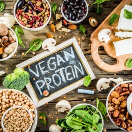 Un blat de lemn pe care se află tofu, semințe de cânepă, nuci și alte surse de proteine pentru persoanele vegetariene și vegane