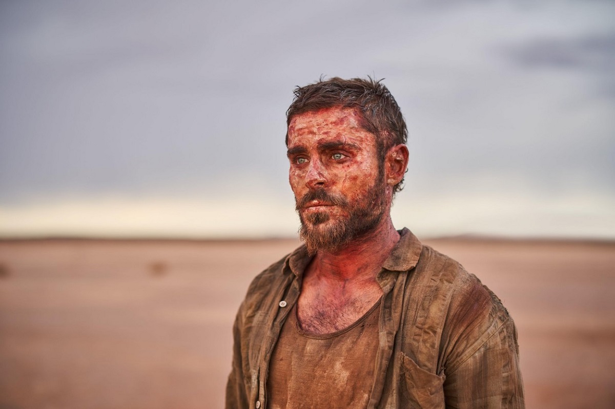Zac Efron cu sânge pe față și plin de nisip în deșert la filmările pentru producția Gold
